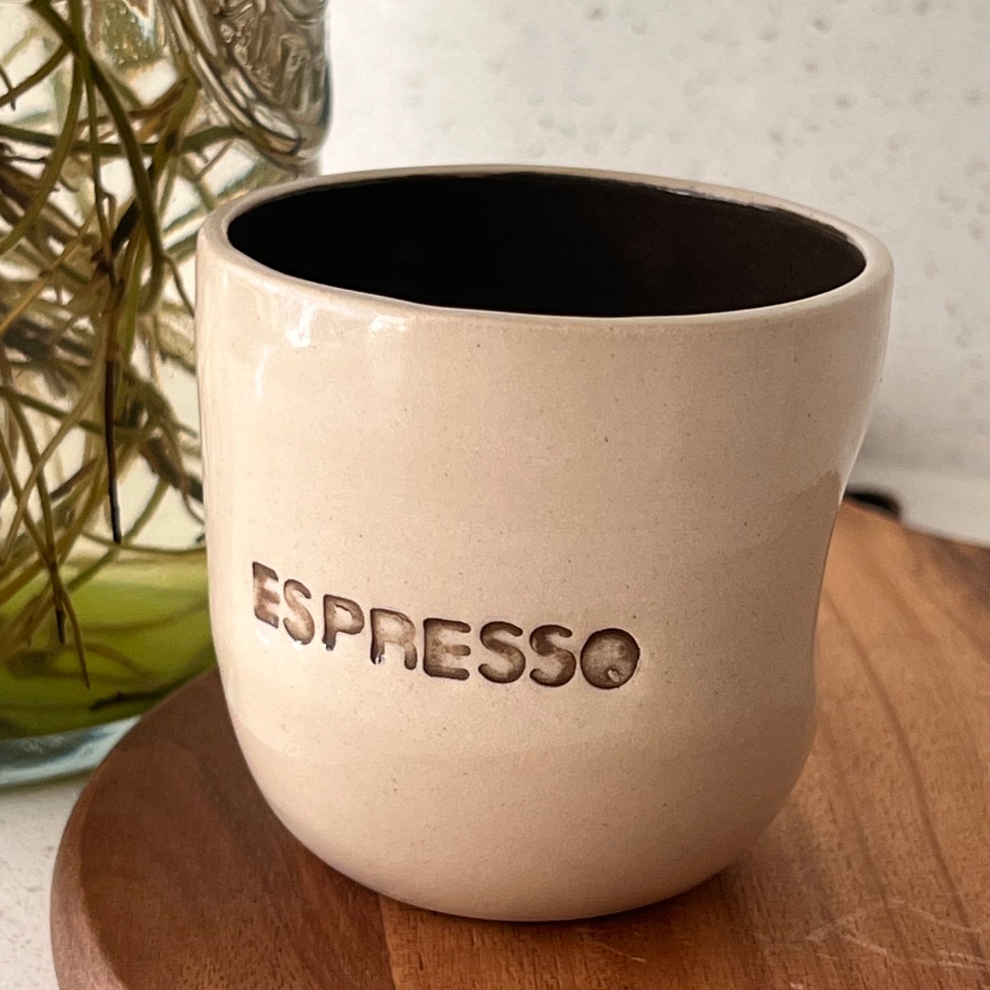 Beige espresso cup with 'ESPRESSO' engraving on a wooden surface