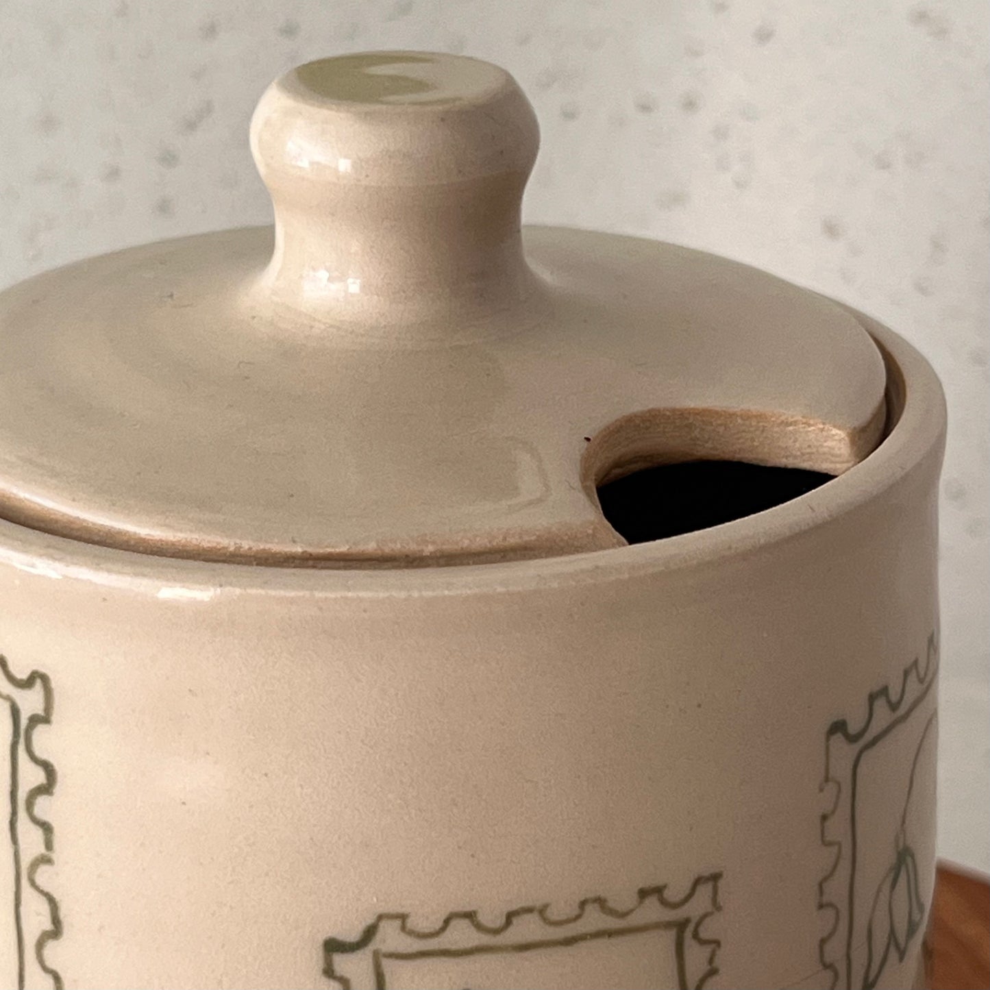 Close-up of a ceramic jar with a lid on a textured surface