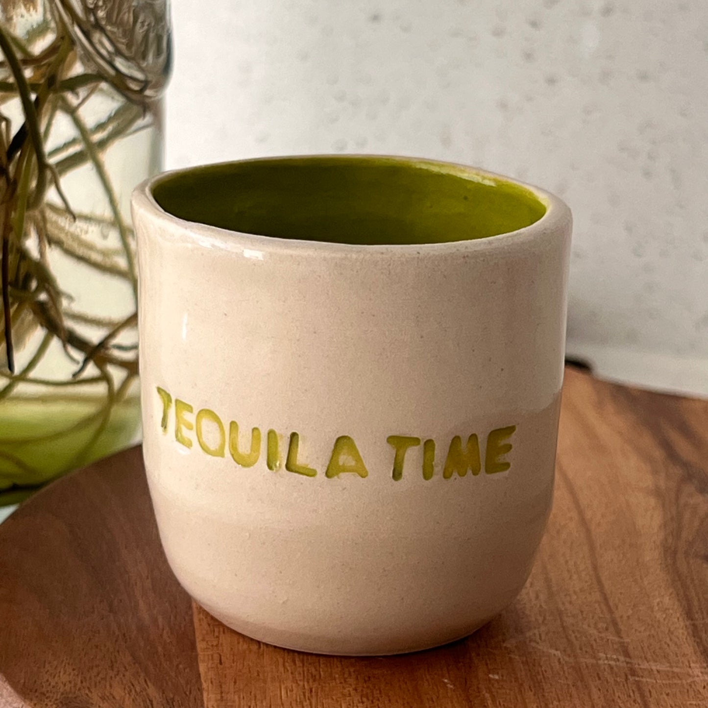 White ceramic cup with 'TEQUILA TIME' text on a wooden surface