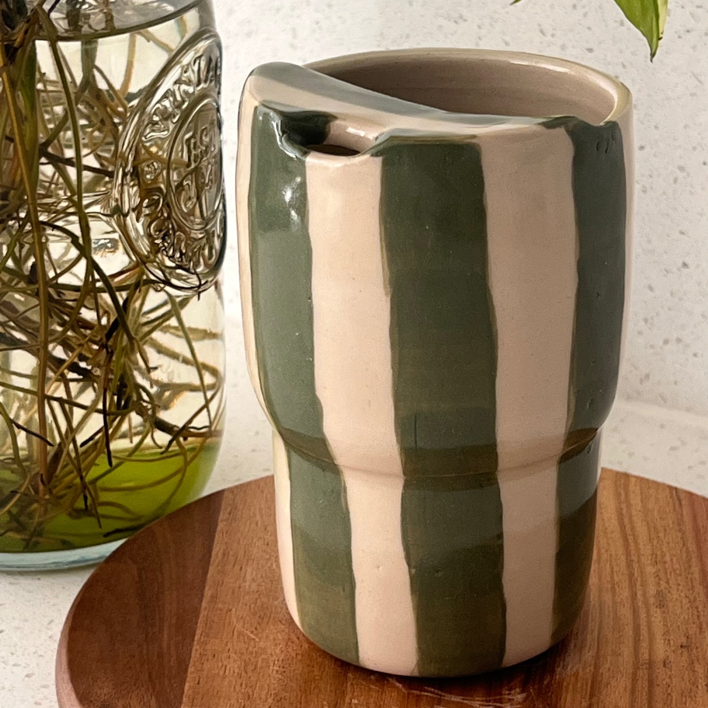 Striped ceramic cup on a wooden surface with a glass jar in the background