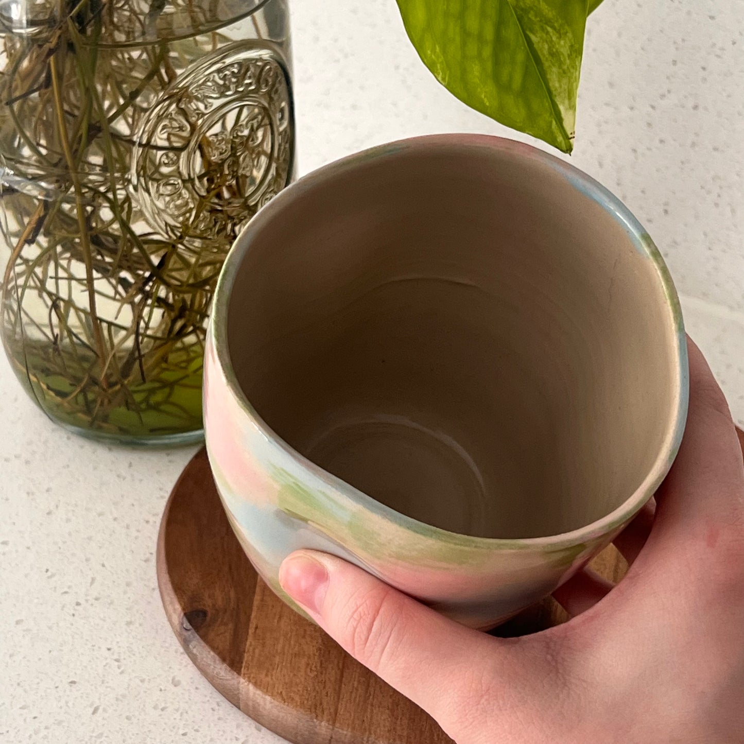 Hand holding a ceramic cup with a blurred background
