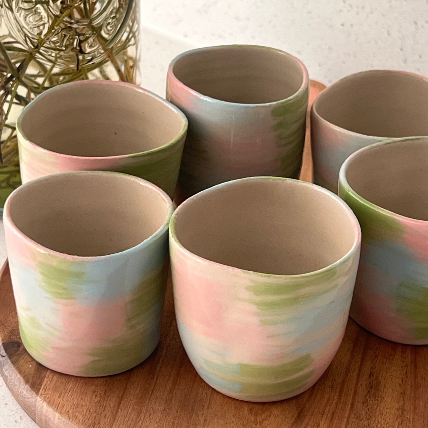 Set of ceramic cups with pastel color patterns on a wooden surface.