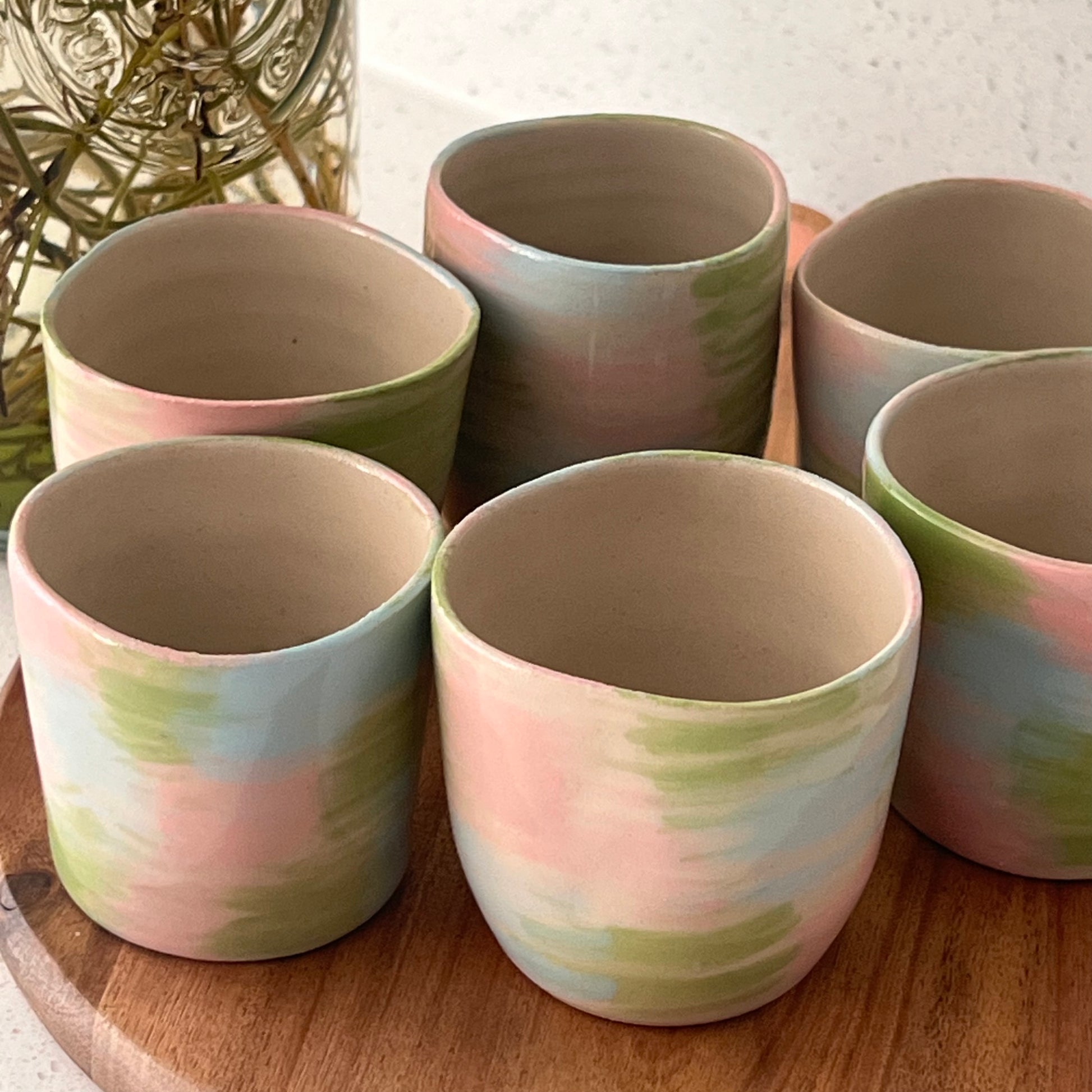 Set of ceramic cups with pastel color patterns on a wooden surface.