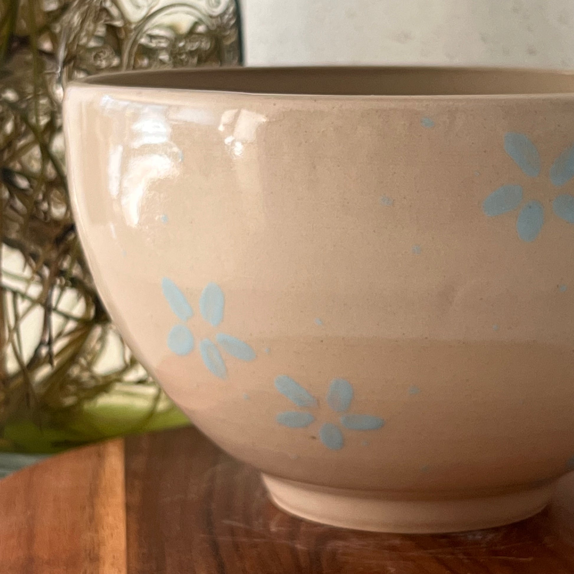 Beige ceramic bowl with blue floral patterns on a wooden surface