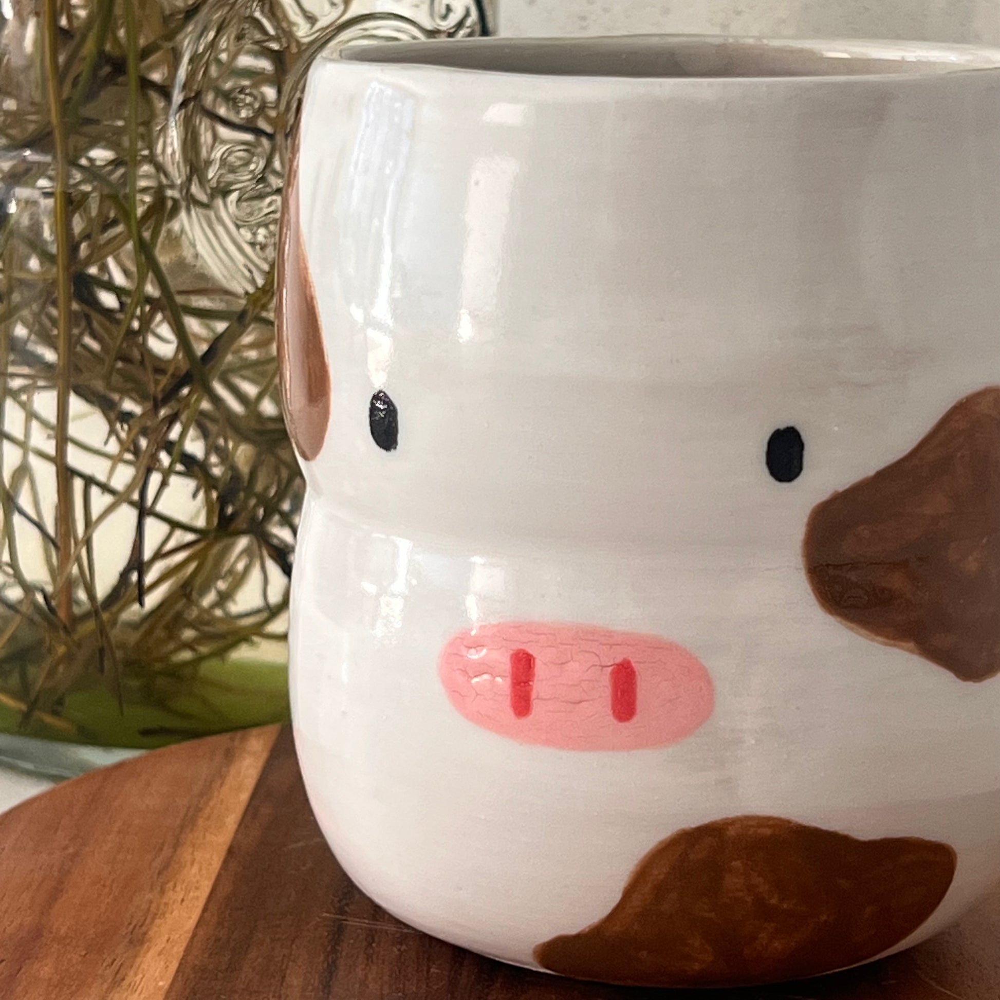 Cow-shaped mug with a pink mouth on a wooden surface